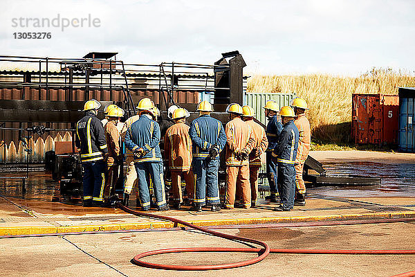 Ausbildung von Feuerwehrleuten  Team von Feuerwehrleuten  die dem Vorgesetzten in der Ausbildungseinrichtung zuhören  Rückansicht