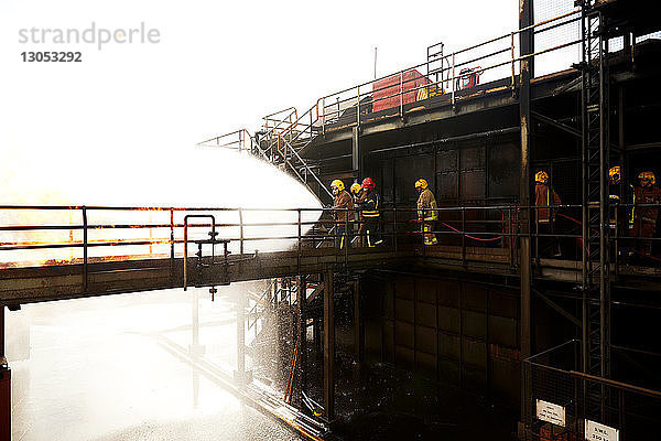 Ausbildung von Feuerwehrleuten  auf einem erhöhten Übungsgelände  auf dem Wasser auf Feuer gesprüht wird