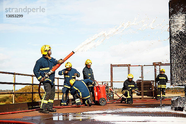 Ausbildung von Feuerwehrleuten  Feuerwehrmänner sprühen Feuerlöschschaum in der Ausbildungsstätte