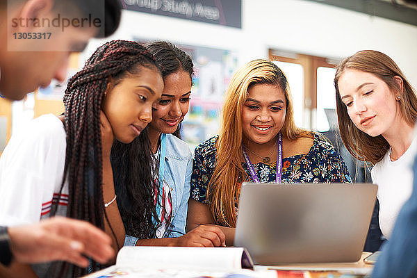 Hochschulstudentinnen und -studenten schauen im College-Klassenzimmer auf den Laptop