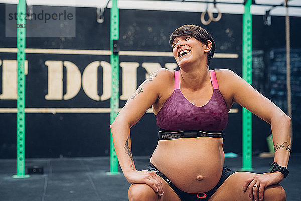 Schwangere Frau lacht im Fitnessstudio