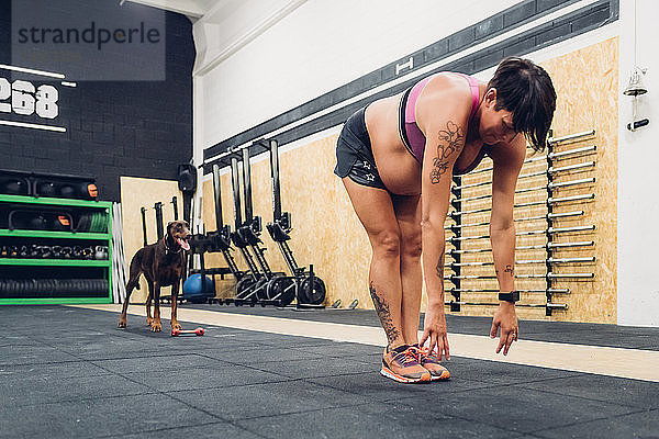 Schwangere Frau beugt sich im Fitnessstudio vor