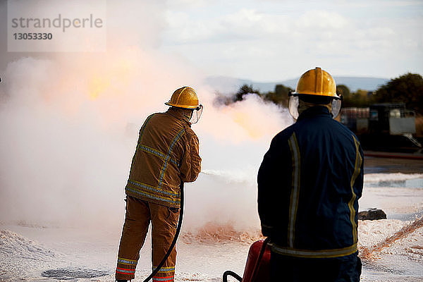 Ausbildung von Feuerwehrleuten  Feuerwehrmänner sprühen Feuerlöschschaum in der Ausbildungsstätte