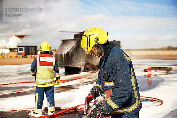 Ausbildung von Feuerwehrleuten  Feuerwehrmänner überprüfen Feuerwehrschlauch nach dem Schein-Hubschrauber-Feuer in Trainingsanlage