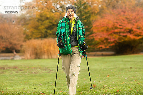 Reife Frau beim Nordic Walking im Park