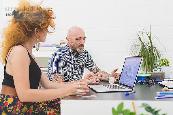 Geschäftsmann und -frau schauen im Büro auf den Laptop