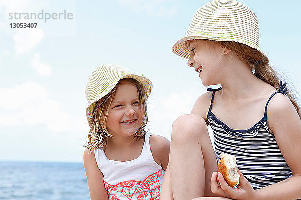 Zwei Mädchen mit Sonnenhüten essen Sandwiches am Strand  Scopello  Sizilien  Italien
