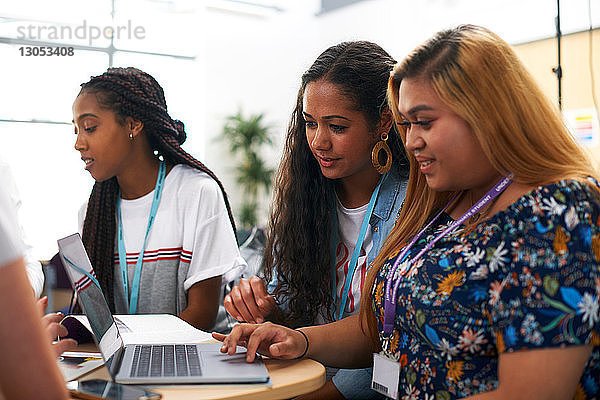 Weibliche und männliche Hochschulstudenten arbeiten im Team und benutzen den Laptop im Klassenzimmer der Hochschule