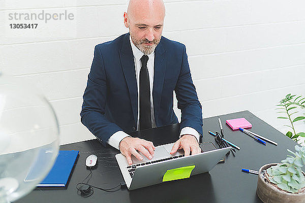 Geschäftsmann tippt am Laptop auf dem Bürotisch