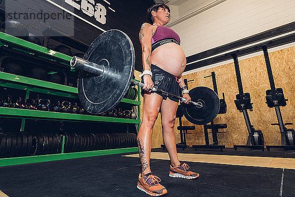 Schwangere Frau benutzt Barglocke im Fitnessstudio