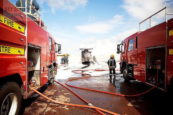 Ausbildung von Feuerwehrleuten  Team von Feuerwehrleuten sprüht Feuerlöschschaum am Scheinhelikopter in der Ausbildungsstätte