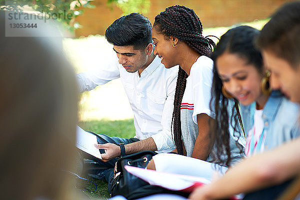 Hochschulstudenten betrachten Papierkram auf dem Rasen des College-Campus  Blick über die Schulter