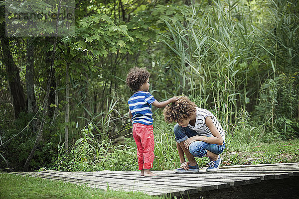 Junge legt im Wald Blatt auf das Haar seiner Schwester