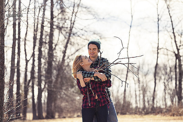 Glücklicher Mann umarmt Frau im Winter im Wald