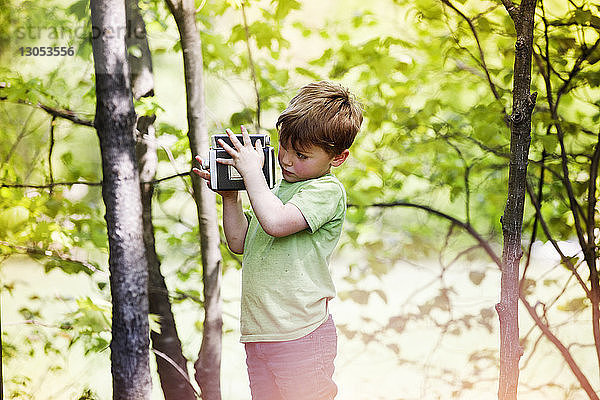 Junge fotografiert durch eine Oldtimer-Kamera im Park