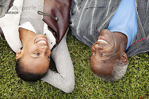 Draufsicht auf Vater und Tochter  die auf einem Grasfeld liegen