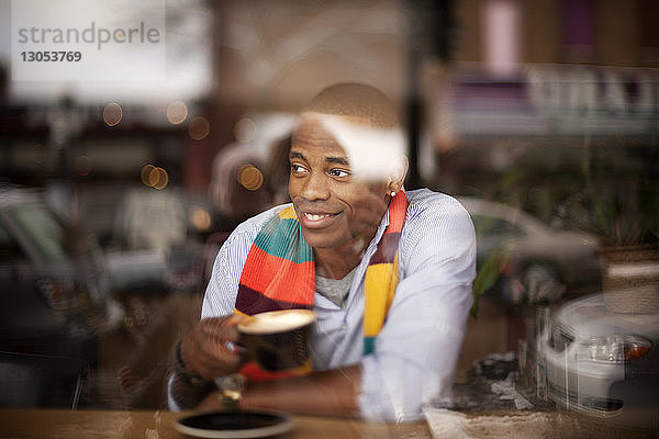 Glücklicher Mann schaut weg  während er im Café sitzt