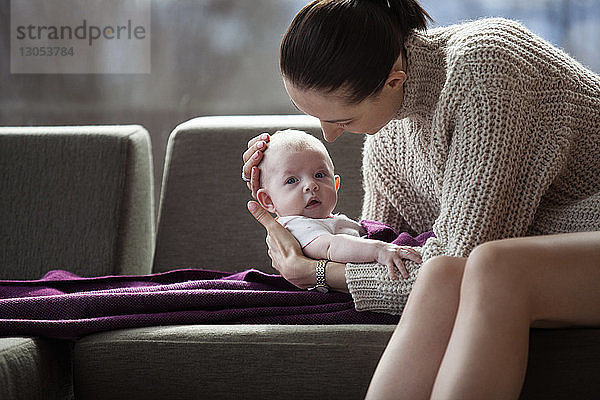 Mutter hält süßes Mädchen zu Hause auf dem Sofa