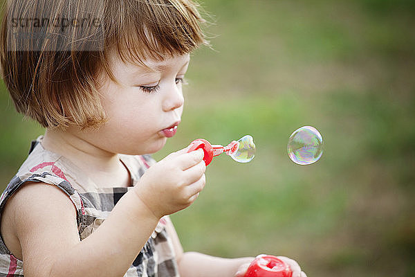 Mädchen bläst Blasen im Park