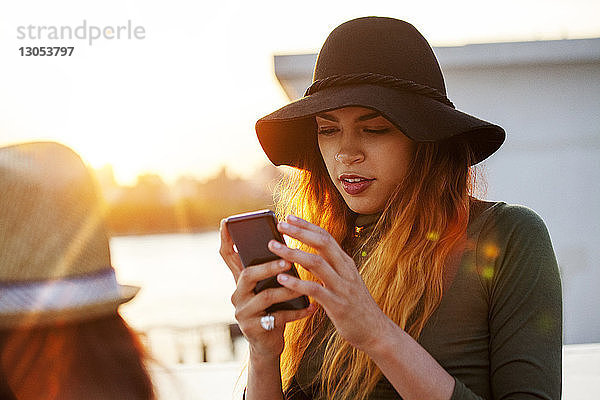 Frau benutzt Mobiltelefon bei Sonnenuntergang