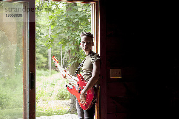 Teenager Junge spielt Gitarre  während er an der Tür steht