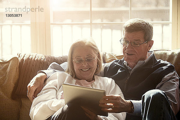 Älteres Ehepaar benutzt Tabletten  während es zu Hause auf dem Sofa sitzt