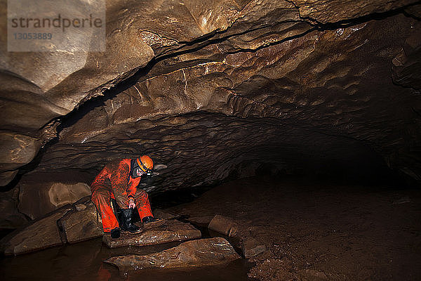 Arbeiter reinigt Stiefel  während er in einer Höhle sitzt