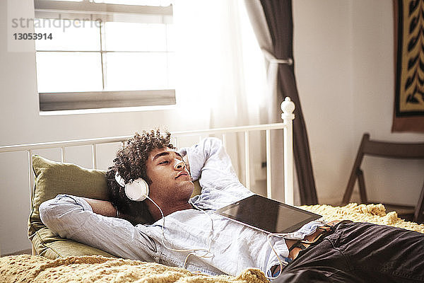 Mann hört Musik  während er sich im Bett entspannt