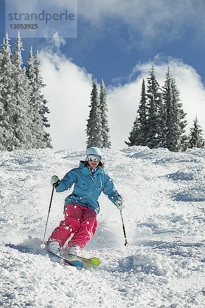Glückliche Frau beim Skifahren am Berg