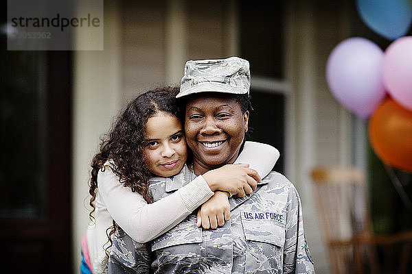 Porträt einer glücklichen Tochter  die Soldat gegen Haus umarmt