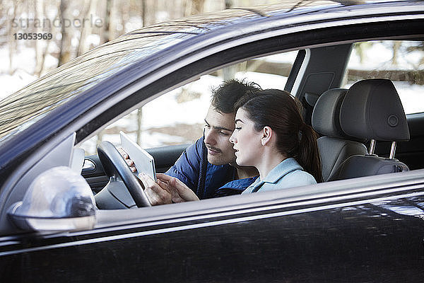 Paar benutzt Tablet-Computer  während es im Auto sitzt