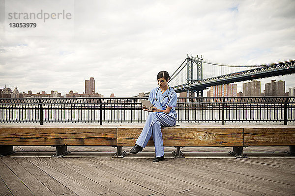 Ärztin sitzt auf Bank gegen Manhattan-Brücke in der Stadt