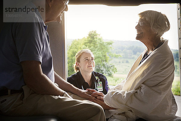 Sanitäter betrachtet Patientin  die mit Ehemann im Krankenwagen sitzt