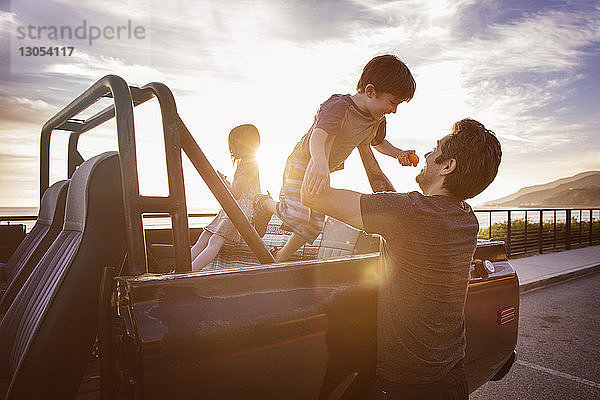 Mann hebt Jungen bei Sonnenuntergang vom Pick-up