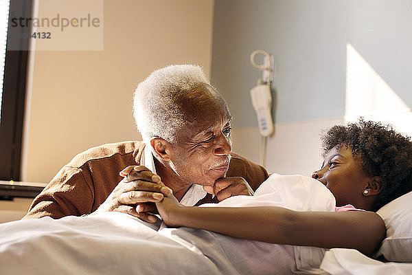 Großvater sieht Mädchen im Krankenhaus im Bett liegen