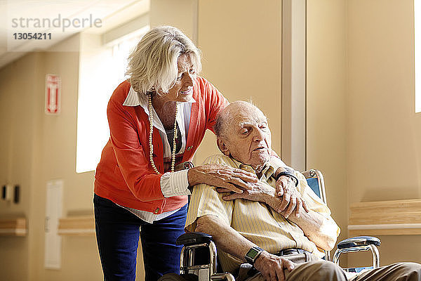 Besorgte Frau mit älterem Mann auf Rollstuhl im Krankenhaus