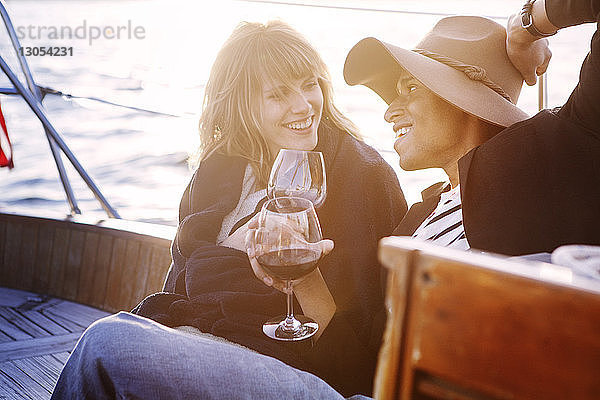 Ehepaar trinkt Rotwein  während es auf einer Yacht sitzt
