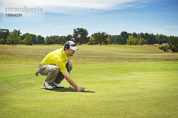 Seitenansicht eines Golf spielenden Mannes auf einem Rasenfeld