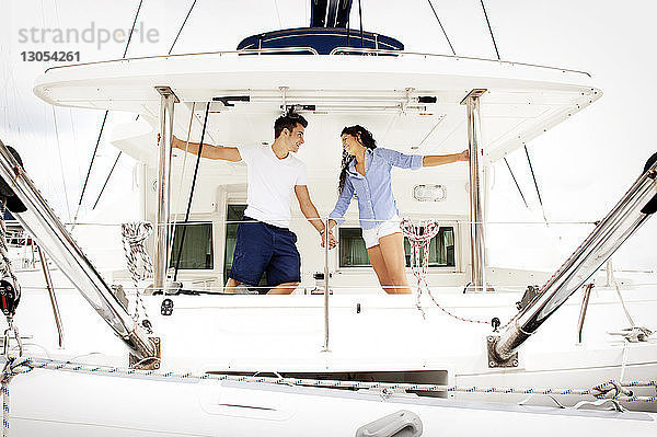 Glückliches Paar hält sich bei einer Romanze im Segelboot an den Händen