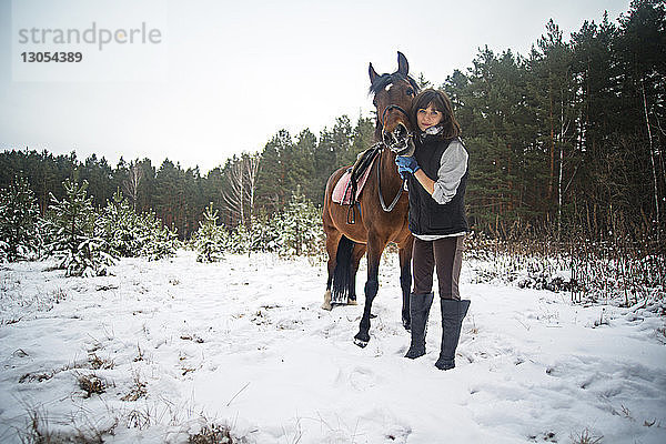 Frau und Pferd stehen auf schneebedecktem Feld