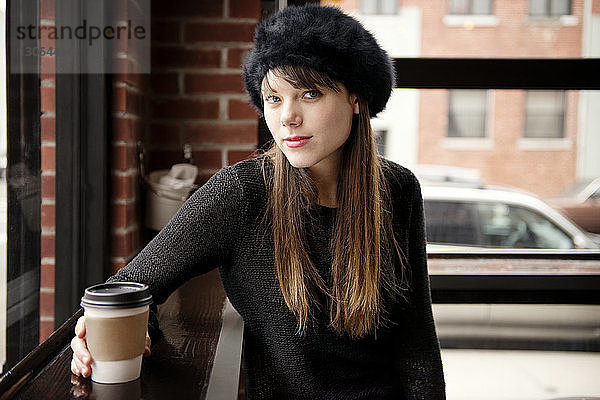 Porträt einer schönen Frau mit Kaffee im Café