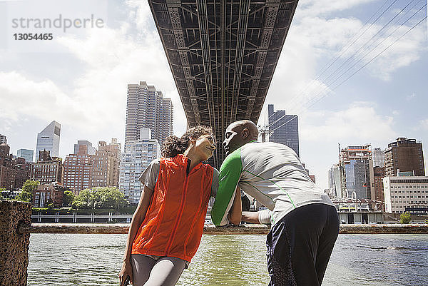 Ehepaar spricht  während es am Geländer unter der Manhattan Bridge steht