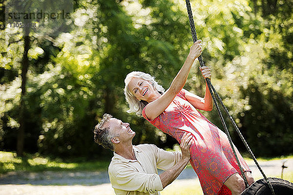 Fröhliches Seniorenpaar spielt auf der Schaukel im Park