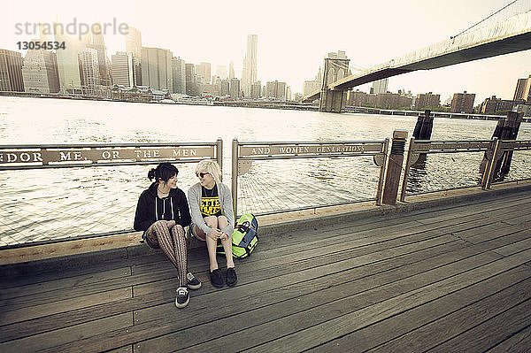 Glückliche Freunde ruhen sich auf der Promenade am East River in der Stadt aus