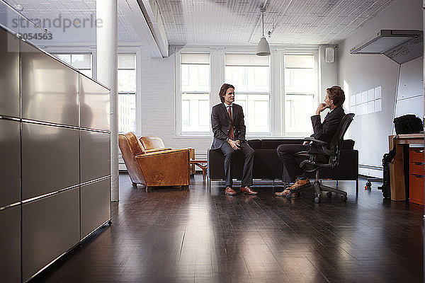 Geschäftsleute diskutieren  während sie im Büro sitzen