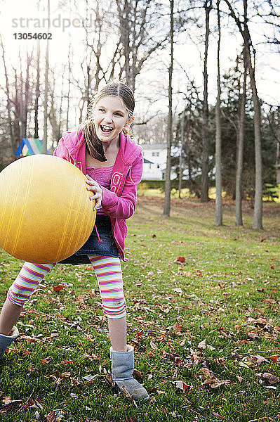 Fröhliches Mädchen spielt mit Ball auf dem Feld