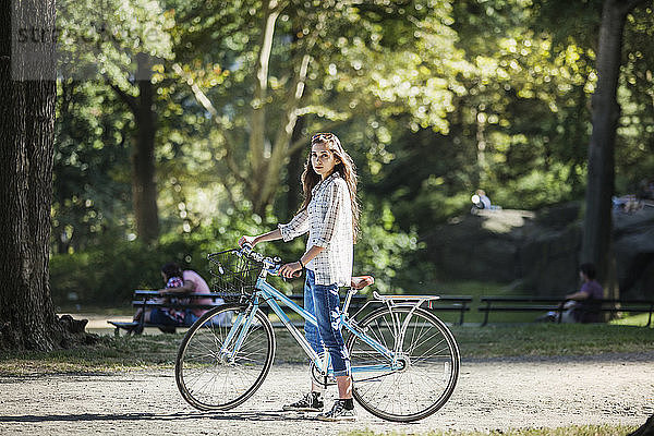 Porträt einer Frau mit Fahrrad auf einem Fussweg stehend