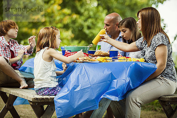 Familie isst Essen  während sie am Picknicktisch sitzt
