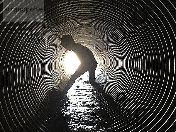 Scherenschnitt Junge steht im Abwassertunnel
