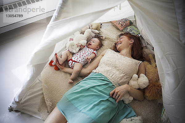 Hochwinkelaufnahme von Mutter und Tochter  die zu Hause im Zelt liegen